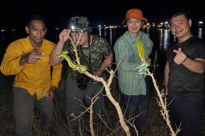 Four people outdoors at night with a body of water and city lights in the background. 2