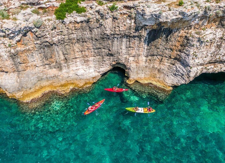 Kayakers in a clear cove surrounded by rocky cliffs. 3