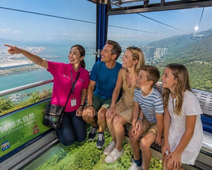 A group of people on a cable car overlooking a coastal landscape with greenery and buildings. 3