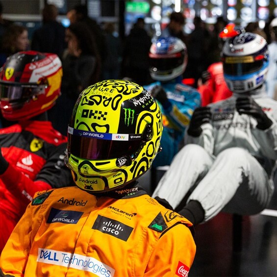 A group of motorcycle racers at a pit stop, wearing helmets and racing suits with various sponsor logos. 5