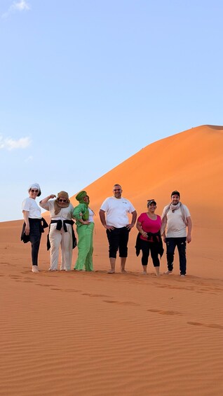 A group of people standing in a desert with sand dunes in the background. 1