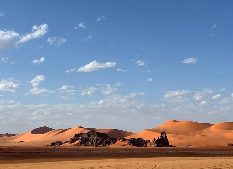 A desert landscape with sand dunes and rocky formations under a clear sky. 3