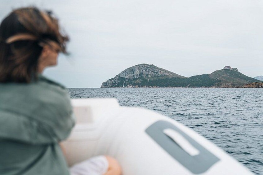 A person on a boat with a view of a rocky coastline. 2