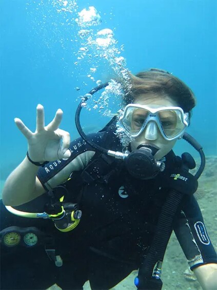 A person scuba diving underwater, wearing a black wetsuit and a scuba mask. 5