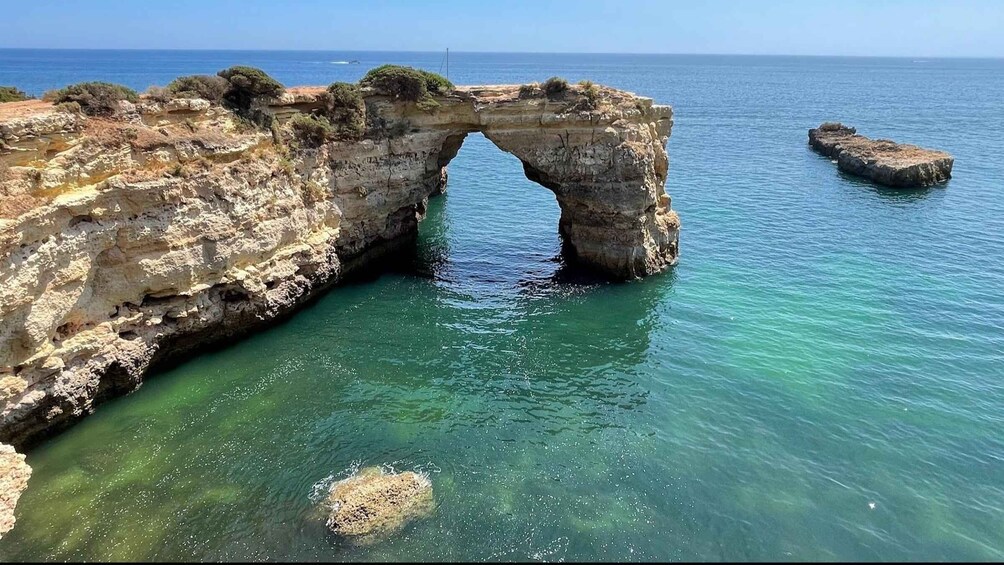 A natural rock arch formation in clear blue waters. 2