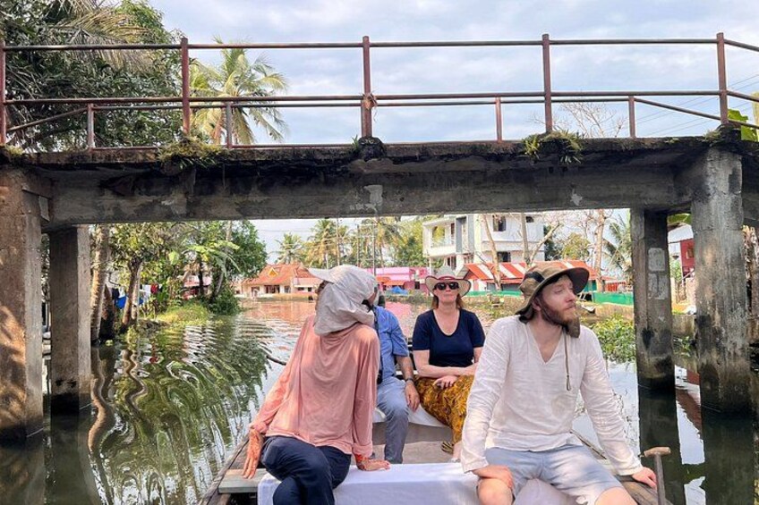 A group of people on a boat under a bridge with water and buildings in the background. 2