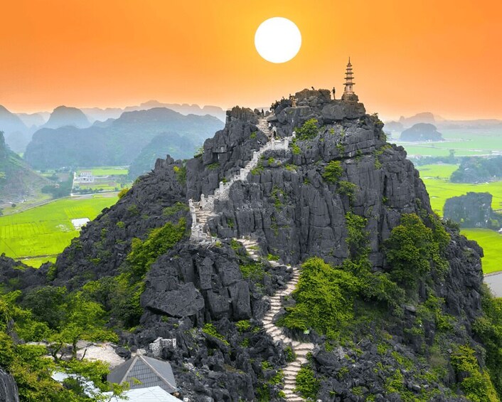 A mountain with a temple at the peak, surrounded by lush greenery and a clear sky. 2