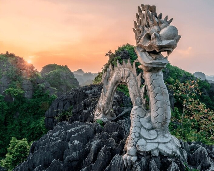 A dragon statue on a rocky outcrop with a sunset in the background. 5