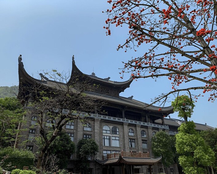A traditional building with ornate architecture, surrounded by lush greenery and a clear sky. 3