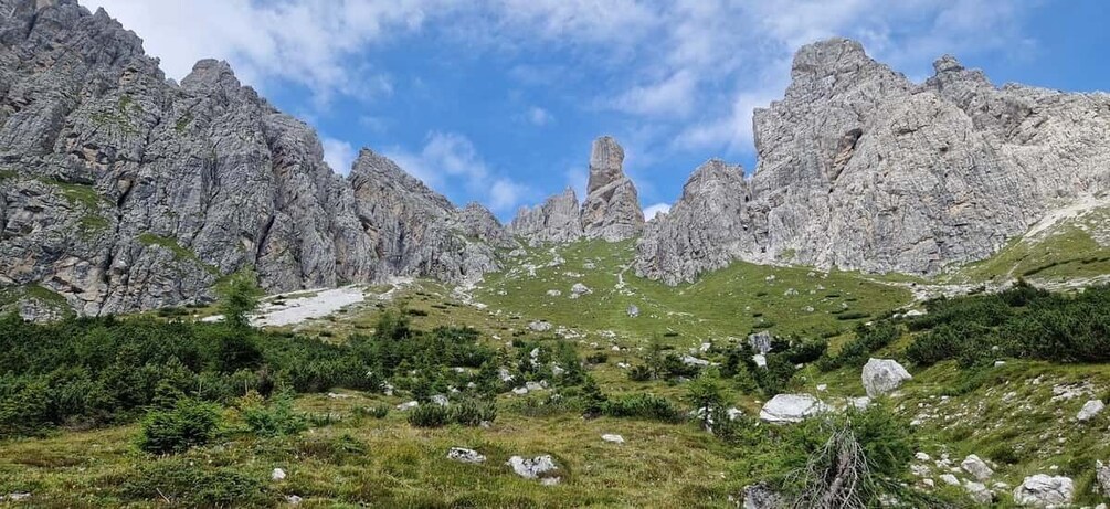 A mountainous landscape with rocky peaks, green vegetation, and a clear sky. 3