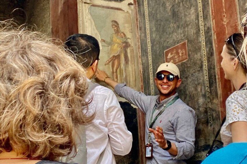 A person pointing at a fresco on a wall. 1