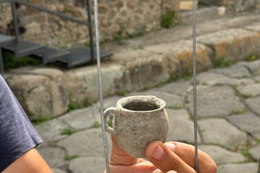A person holding a small, rustic ceramic mug. 3