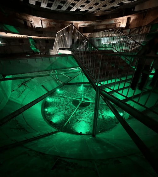 A dimly lit, circular room with a central pillar and a staircase leading to a higher level. 4