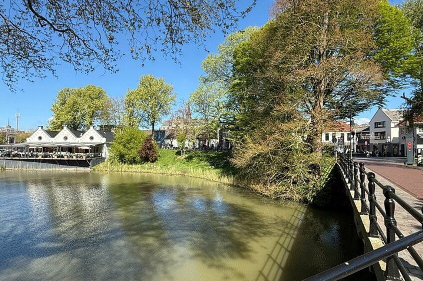 A calm river with a bridge, trees, and buildings along the banks. 2
