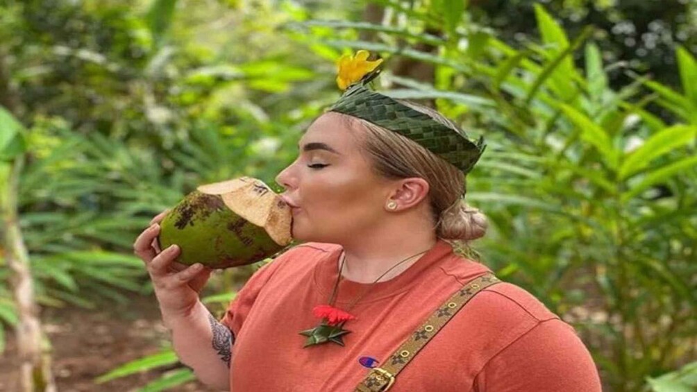 A person wearing a green hat and a red shirt, holding a green coconut. 5
