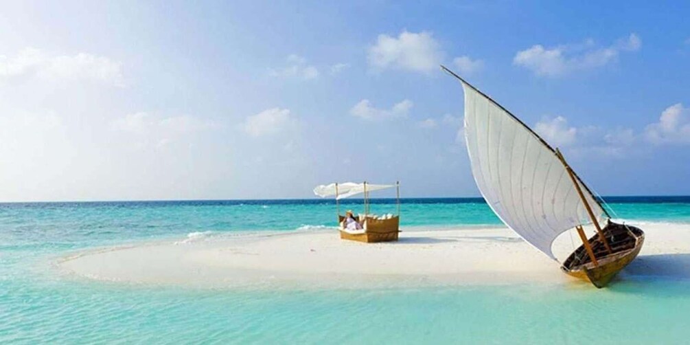 A sailboat on a sandy beach with a parasail and a small boat with people on it. 3