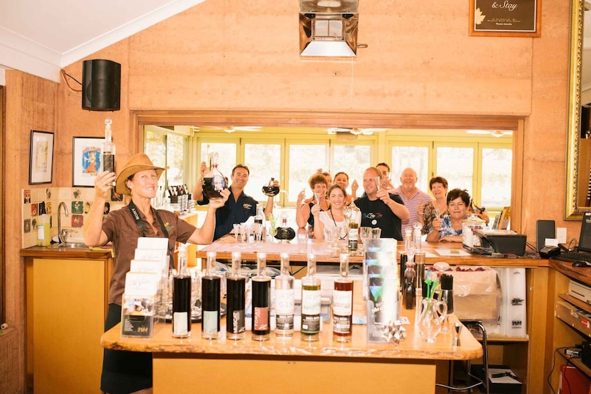 A group of people in a bar setting with a variety of bottles and glasses on the counter. 2