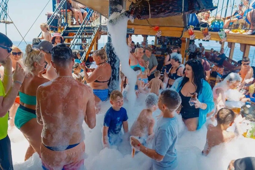 A group of people enjoying a water activity, possibly a water slide or fountain, with foam and water splashing around. 1