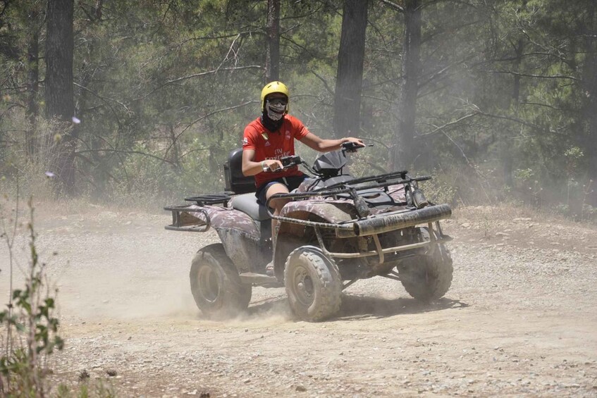 A person riding a quad bike on a dirt path in a wooded area. 1