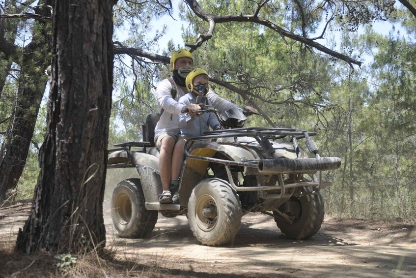 A person riding an ATV on a dirt path in a wooded area. 5