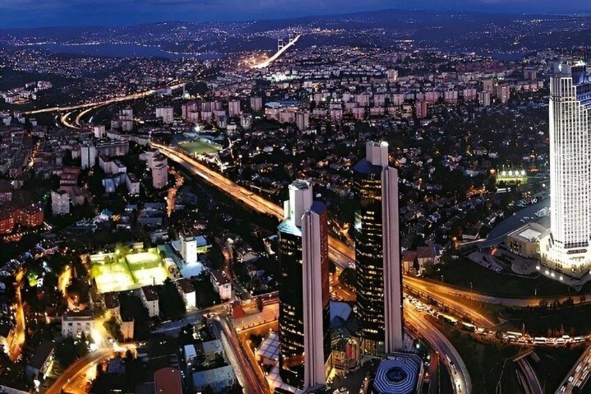 A cityscape at night with illuminated buildings, roads, and a prominent tower. 2