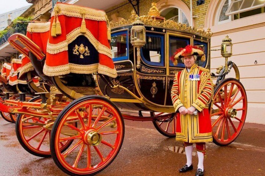A horse-drawn carriage with ornate decorations and a uniformed individual standing beside it. 1