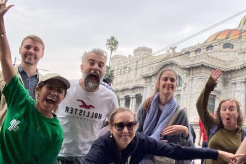 A group of people posing in front of a historic building with ornate architecture. 3