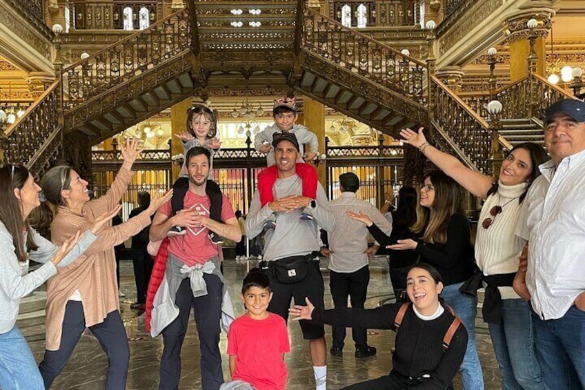 A group of people in a grand, ornate building with a large staircase and intricate railings. 4