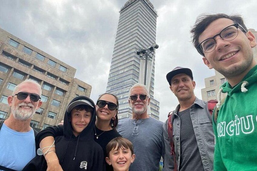 Un grupo de personas frente a un edificio alto bajo un cielo nublado. 1