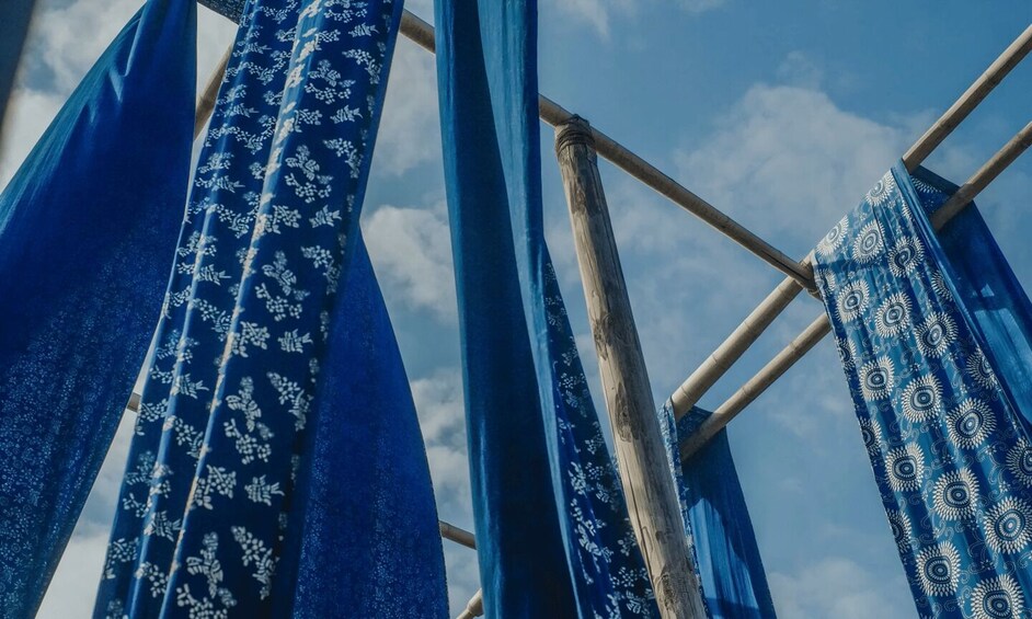 Blue patterned fabric hanging on a wooden structure against a sky. 3