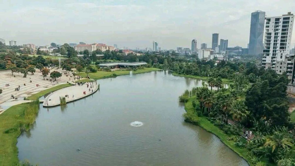 A large body of water surrounded by greenery, a few buildings, and a distant city skyline. 2