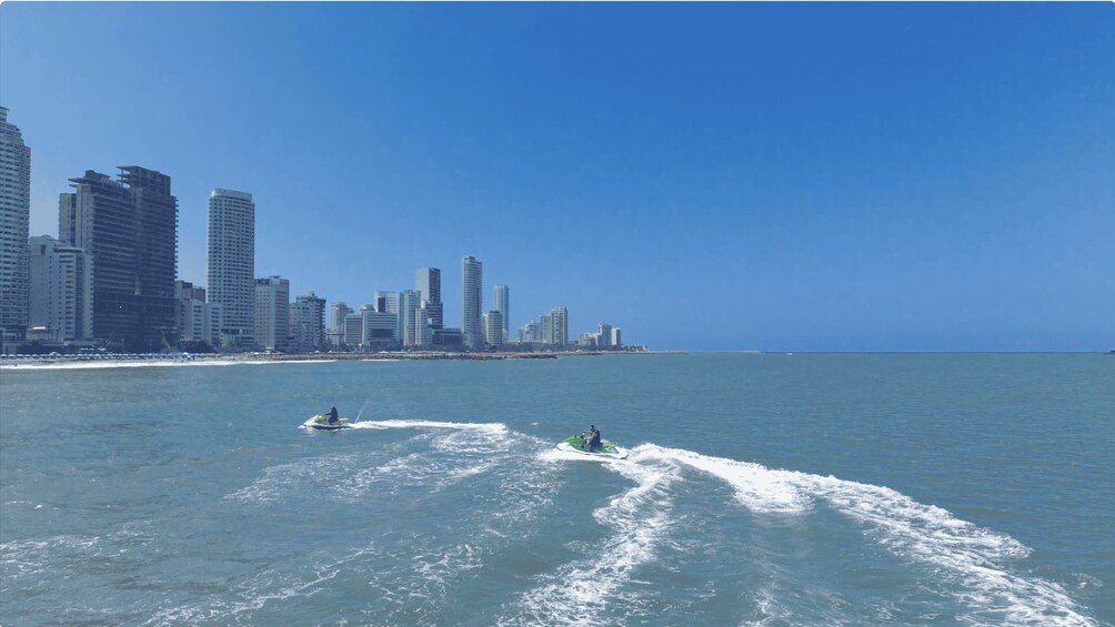 A coastal cityscape with high-rise buildings and two jet skis on the water. 3