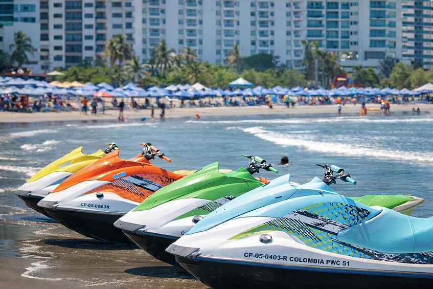 Jet skis lined up on a beach with a cityscape in the background. 4
