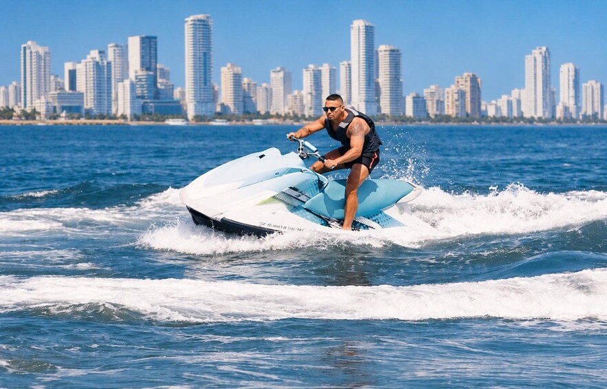 A person jet skiing on a body of water with a city skyline in the background. 1