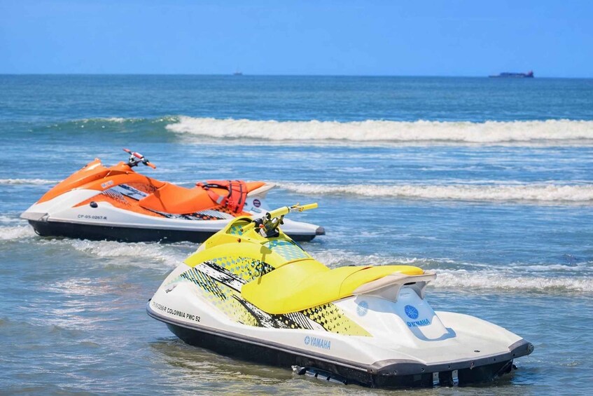 Two jet skis on a calm sea with waves, one orange and one yellow, with a clear sky in the background. 5