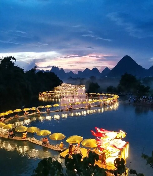 A river with boats and people, surrounded by mountains and a sunset sky. 5