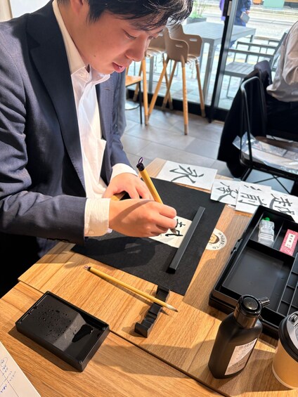 A person writing calligraphy on paper with a brush. 1