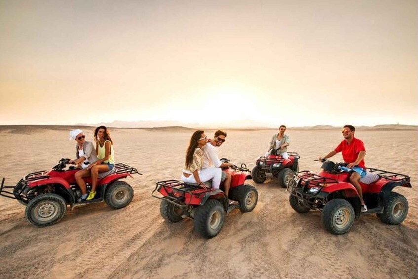 People riding ATVs on a sandy terrain with a sunset in the background. 5
