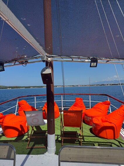 A sailboat deck with orange cushions and a view of the sea. 3