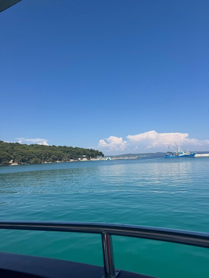 A calm sea with a clear sky, a distant shoreline with greenery, and a blue boat in the water. 5