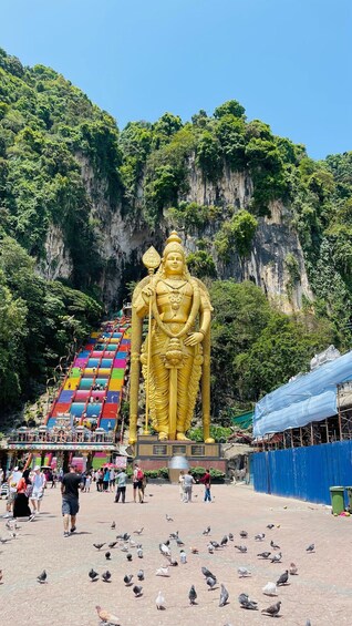 A large golden statue of a deity with a temple and colorful stairs in the background. 1