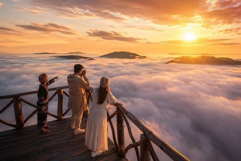 A wooden observation deck overlooking a sea of clouds with a sunset in the background. 3