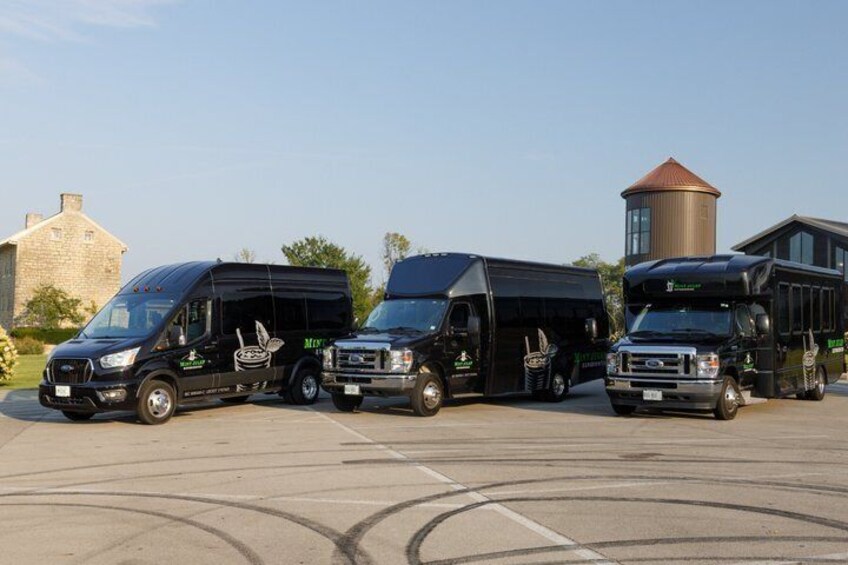 Three black food trucks parked in a lot with a building and a silo in the background. 2