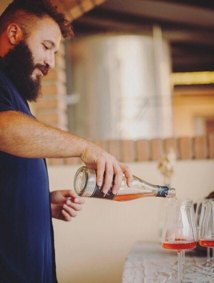 A person pouring a liquid from a bottle into glasses. 5