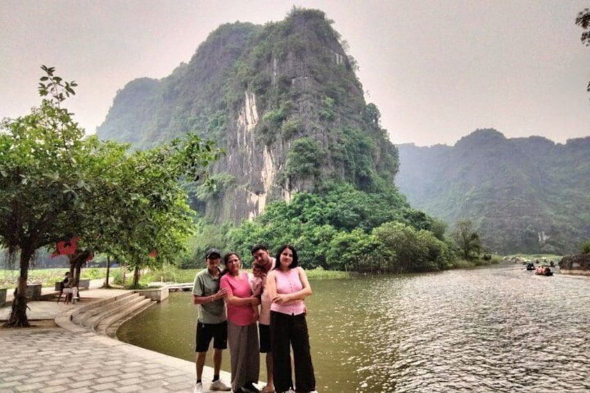 A group of people standing by a river with a mountainous backdrop. 1
