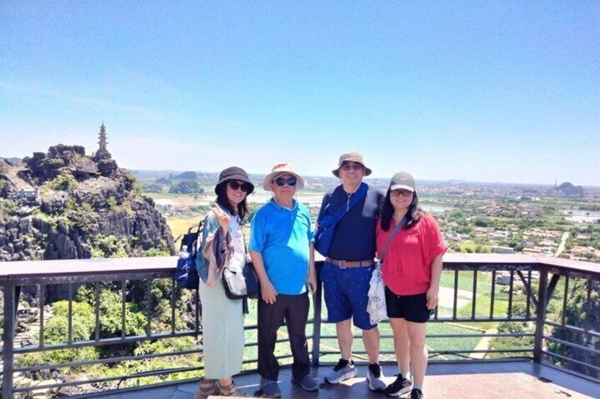 A group of people standing on a viewing platform with a scenic landscape in the background. 1