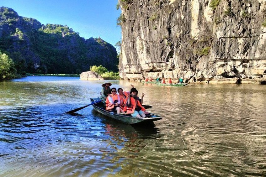 A group of people in a boat on a river with rocky cliffs in the background. 4