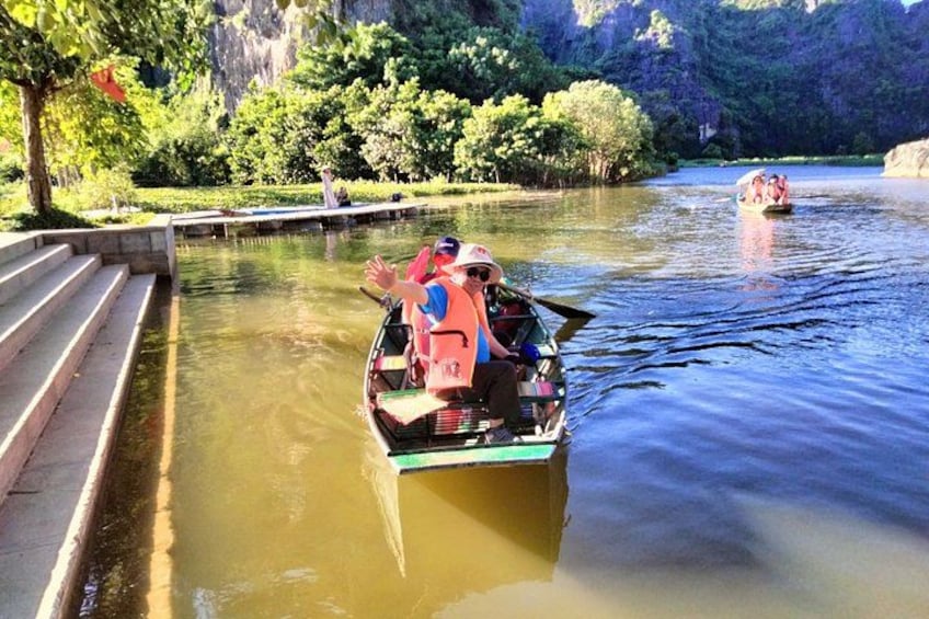 A river with a boat carrying passengers, surrounded by lush greenery and a bridge. 5