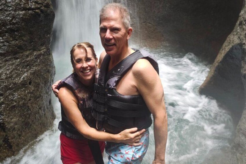 Two people standing by a waterfall. 1