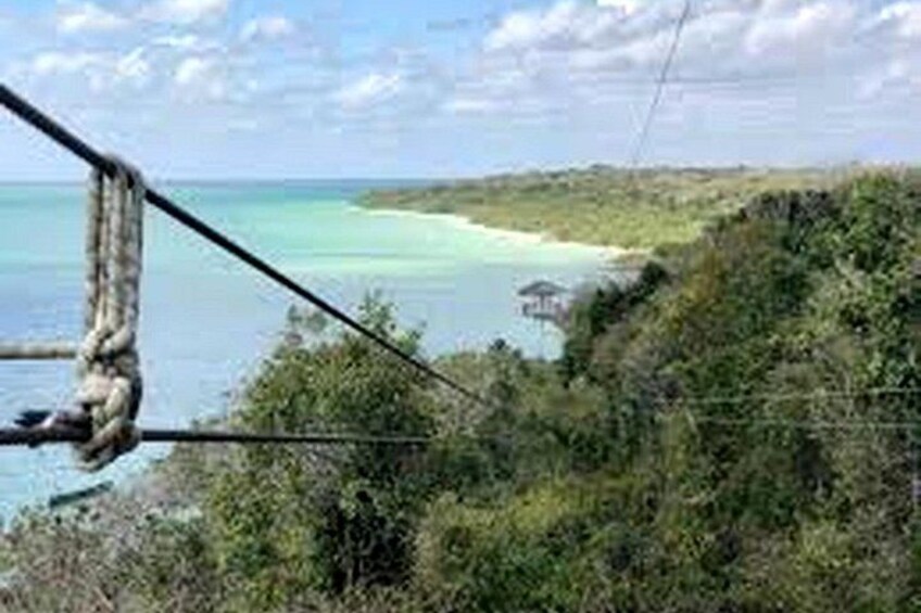 Eine Seilbrücke über ein Gewässer, einen Strand und einen bewaldeten Bereich. 5